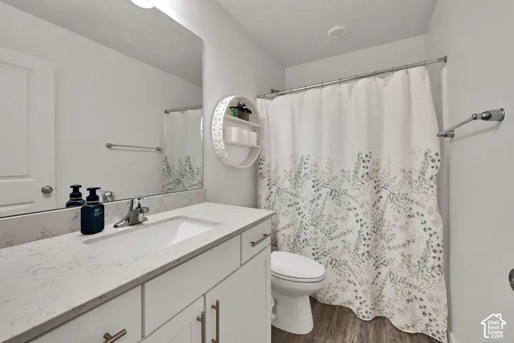 Bathroom featuring a single vanity with an integrated sink, light-toned countertop, and wood-finish flooring