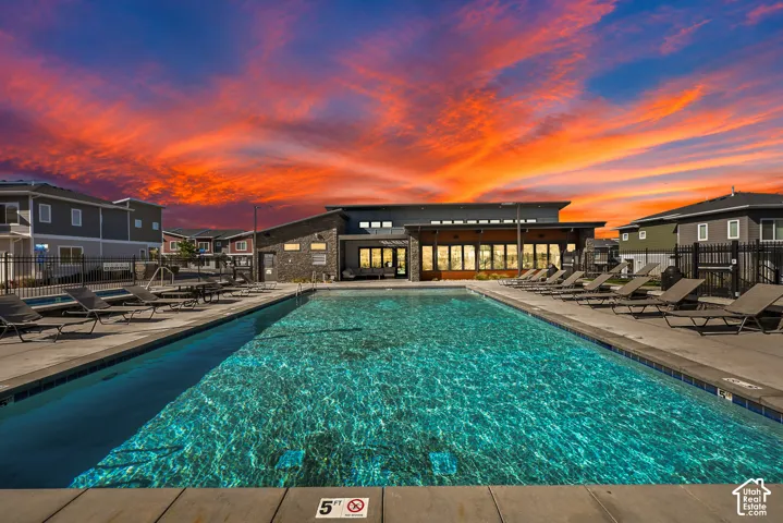 Swimming pool with concrete surround, lounge seating, and a modern clubhouse structure- community has pickleball and exercise clubhouse