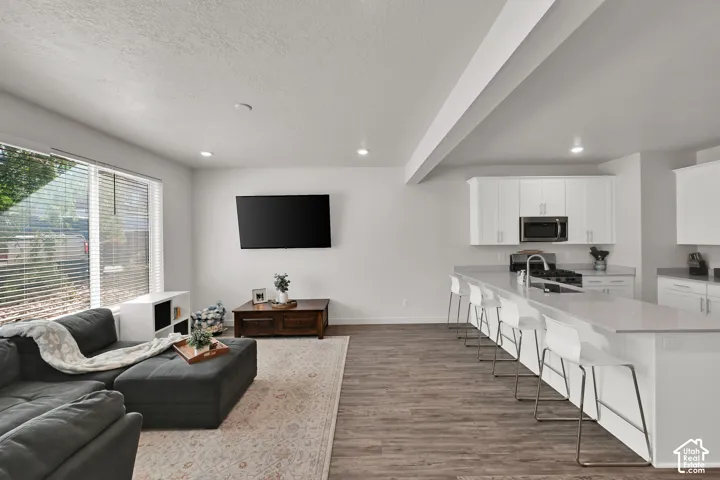 Open-concept living space featuring wood-finish flooring, recessed lighting, and a large window