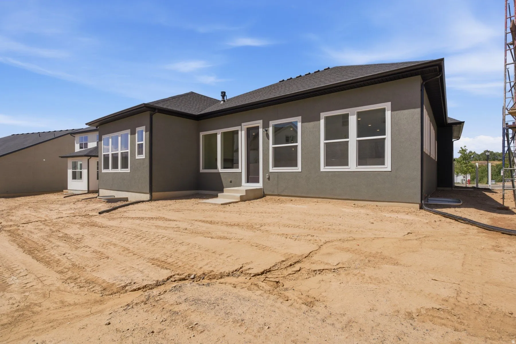 Contemporary exterior with stucco finish, multiple large windows, dark roof, and dark trim