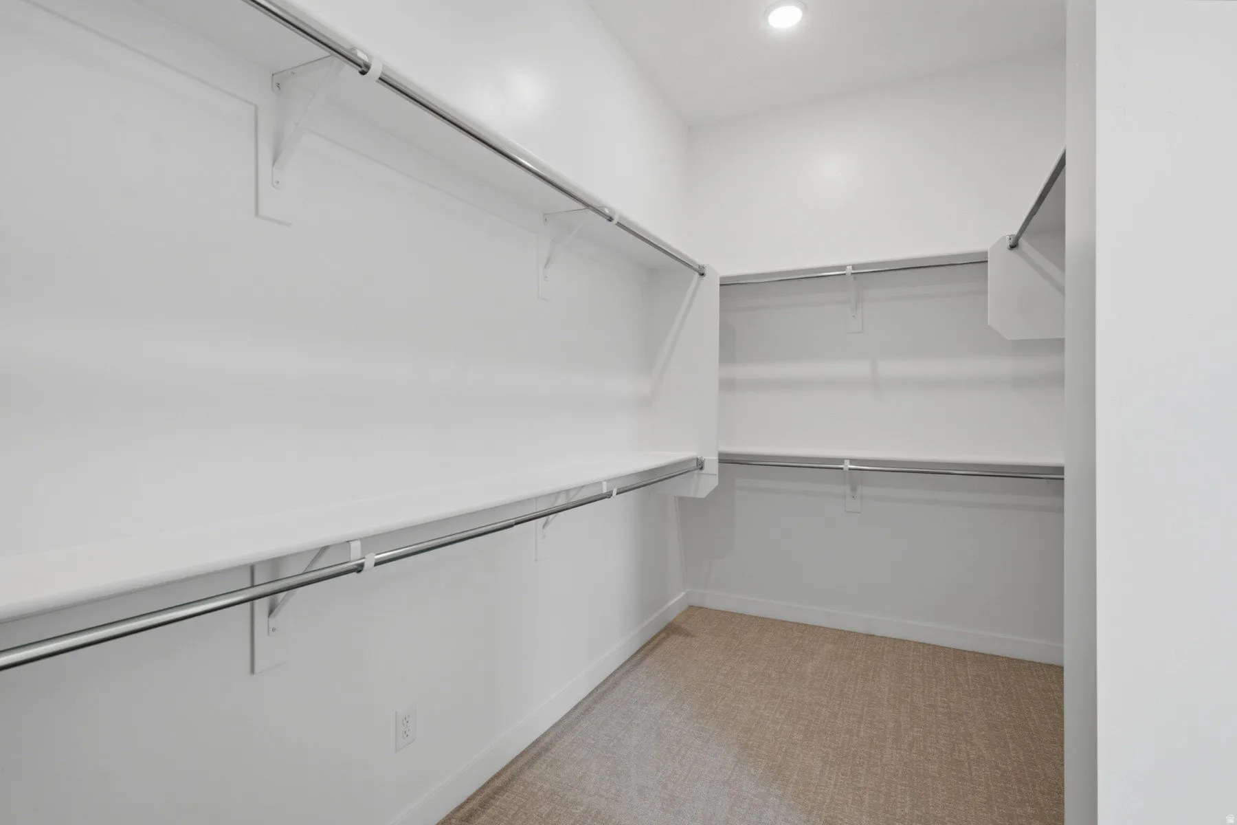 White shelving system with chrome hanging rods, recessed ceiling lighting, and carpet flooring