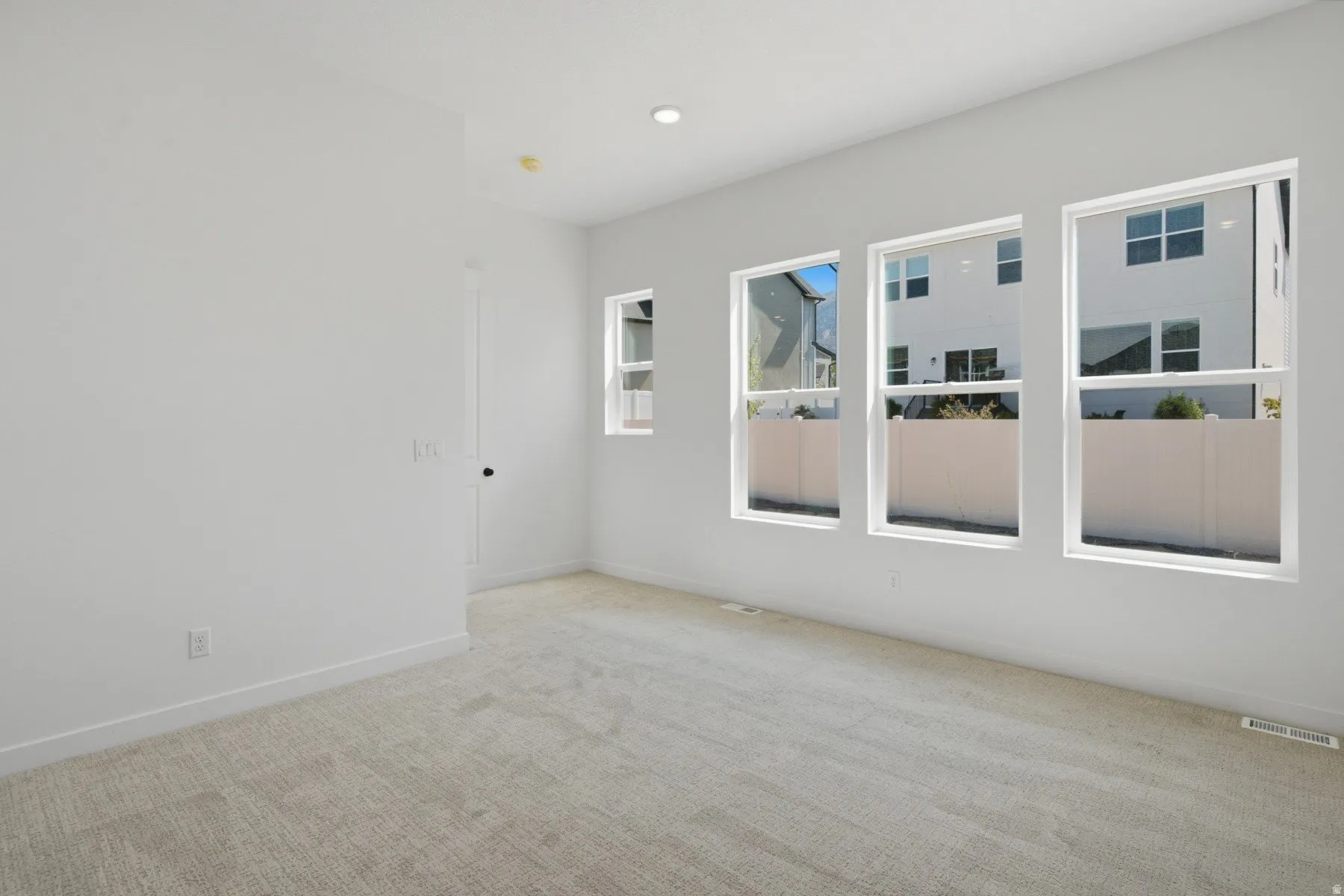 Recessed lighting, light-toned carpeting, and a white interior door with a black handle