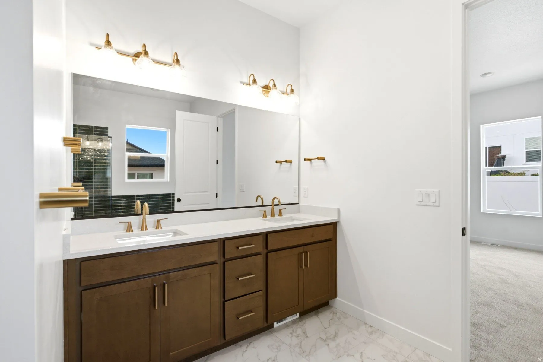 Dual vanity with brown wood-finish cabinetry, white countertop, and gold-finish fixtures
