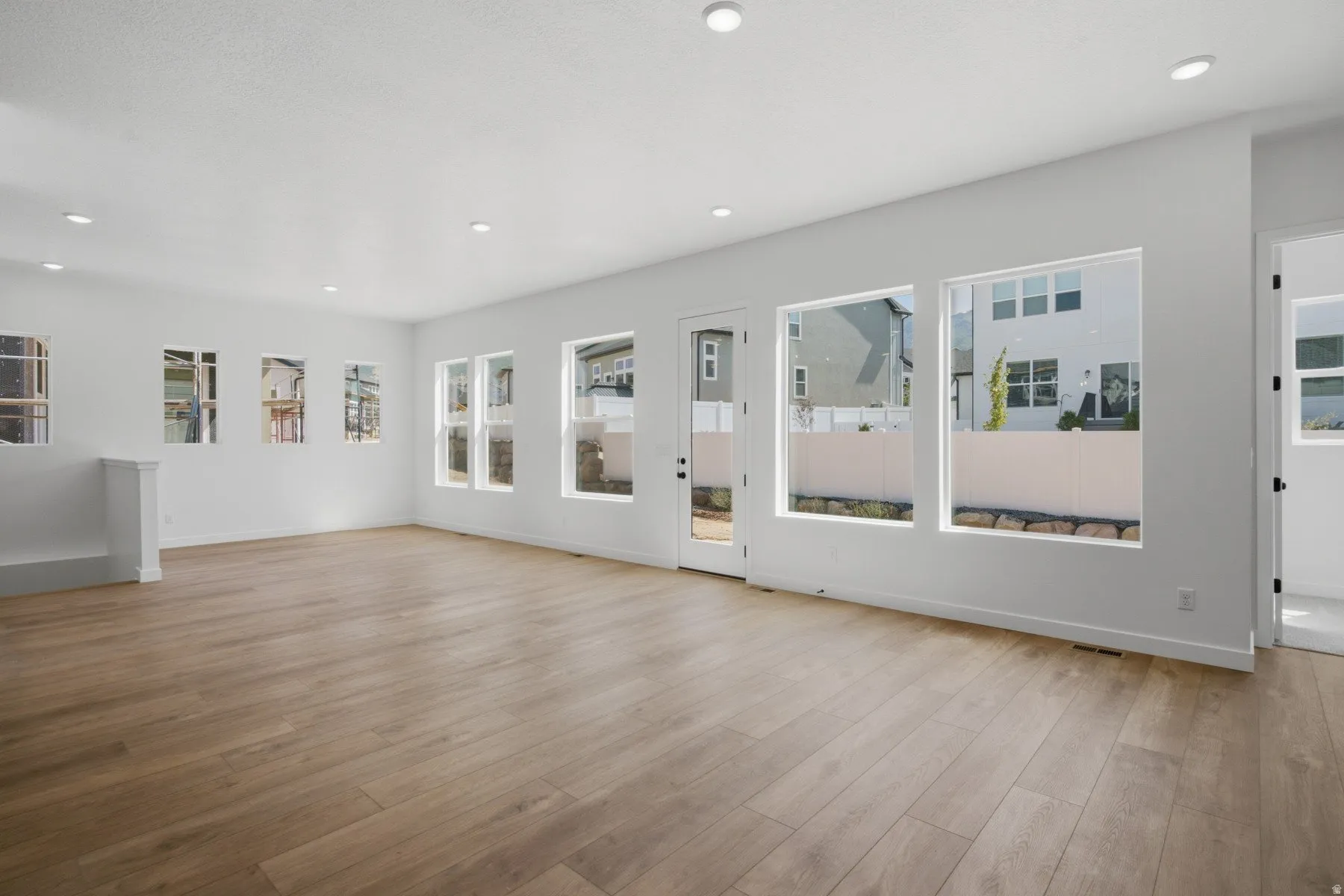 Expansive room featuring wood-finish flooring, ample natural light from multiple windows, and recessed lighting