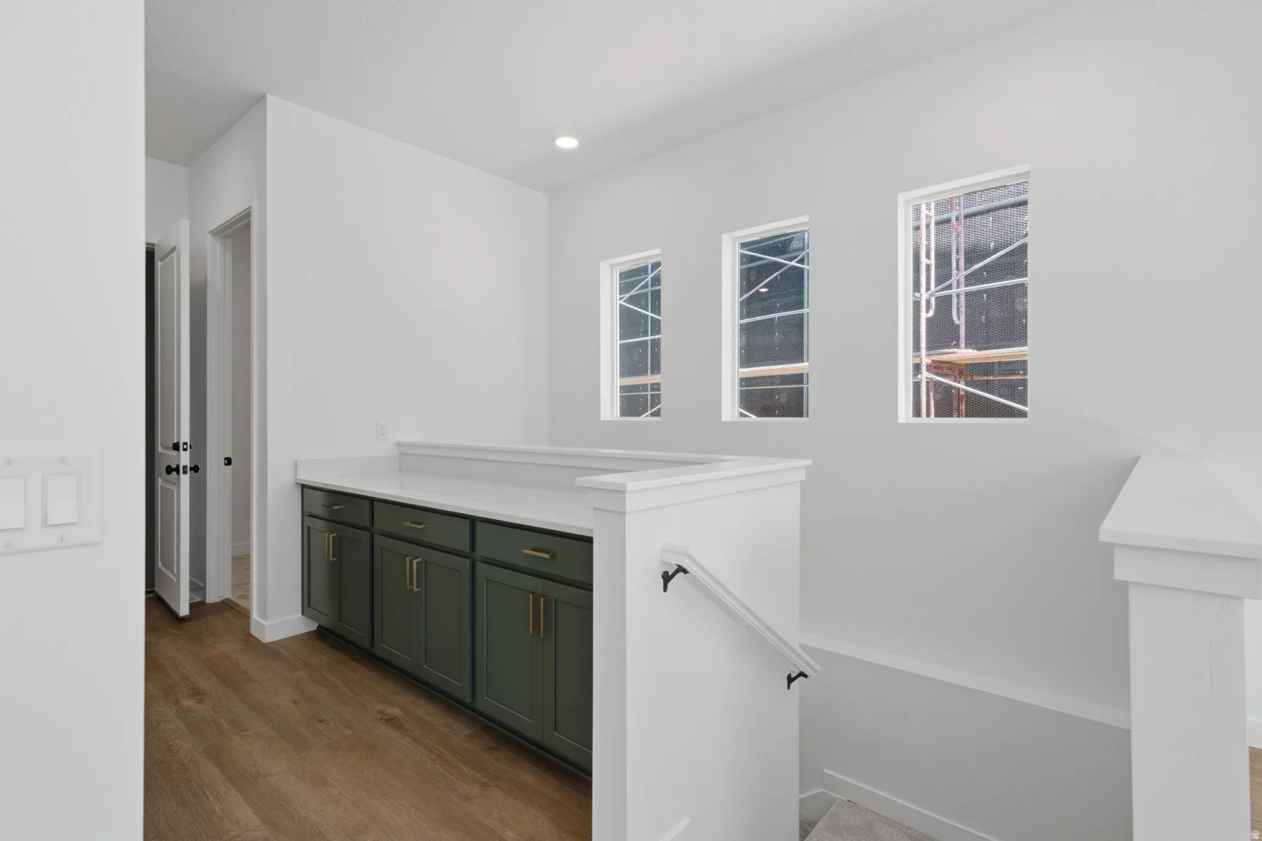 Built-in cabinetry with gold-finish hardware, quartz countertop, wood-finish flooring, and recessed lighting