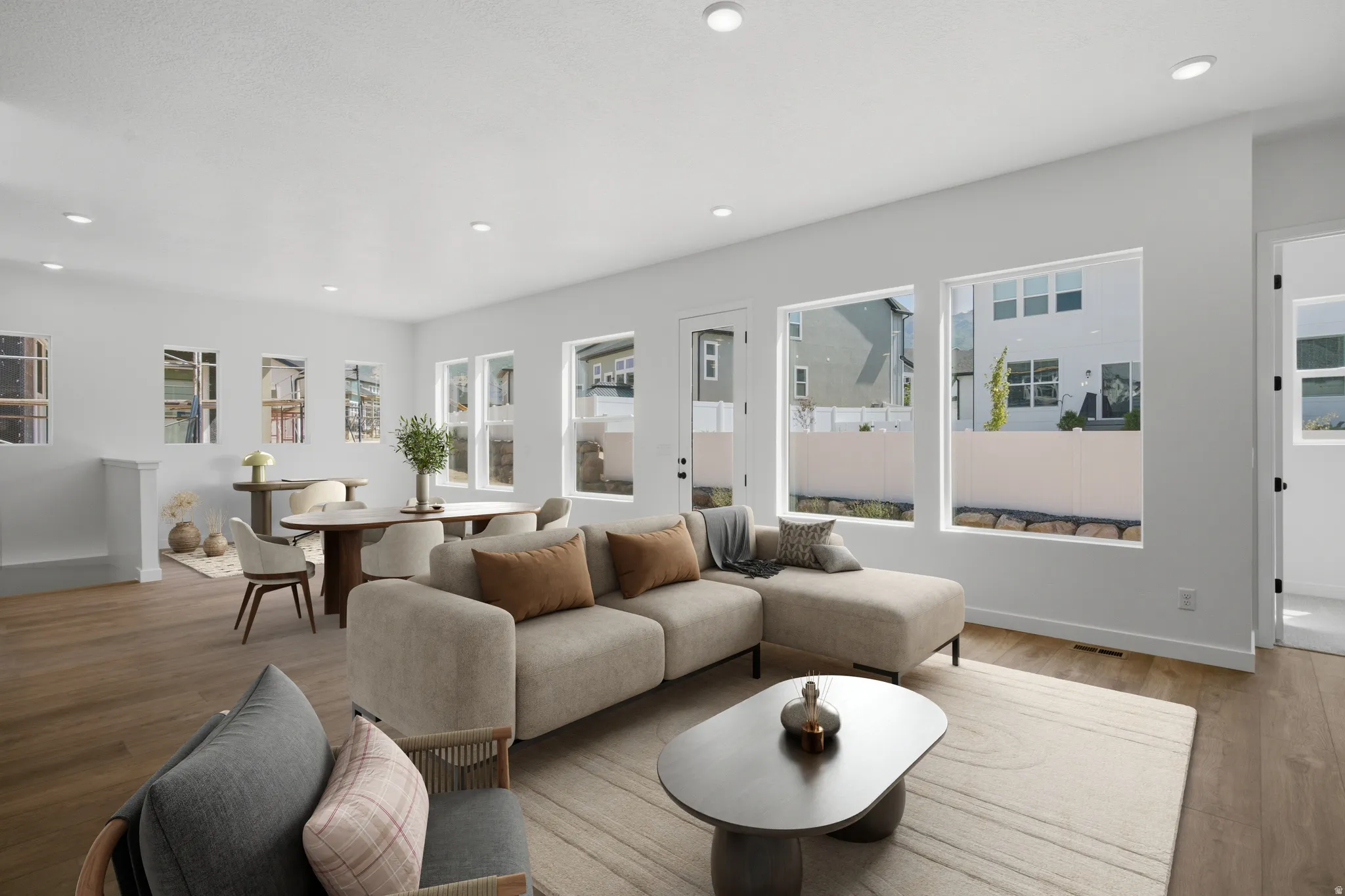 Recessed lighting illuminates an open-concept living area with wood-finish flooring