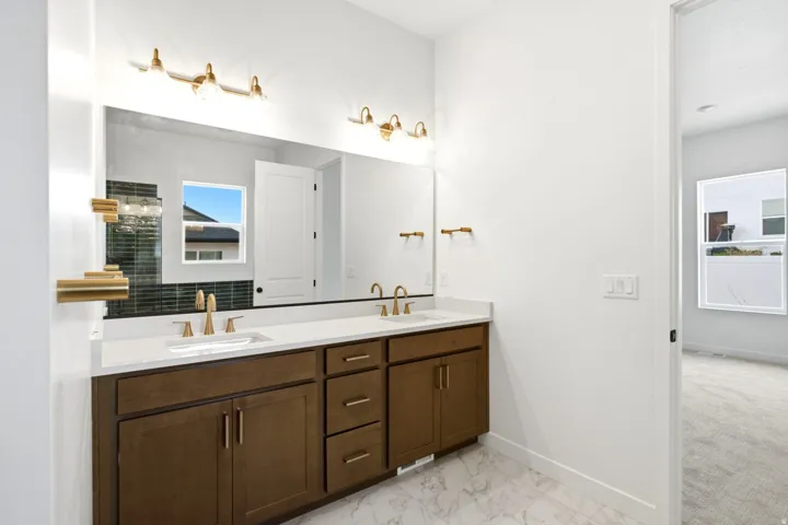 Dual vanity with brown wood-finish cabinetry, white countertop, and gold-finish fixtures