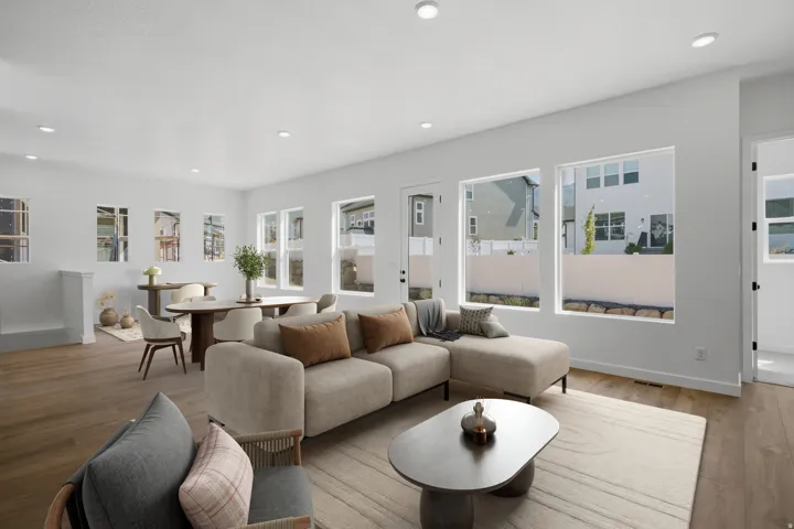 Recessed lighting illuminates an open-concept living area with wood-finish flooring