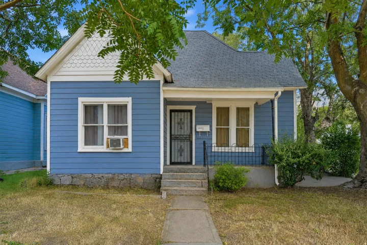 WITHOUT SHADOWS. Blue horizontal siding facade with white trim, a dark shingle roof, and a covered front porch featuring a black security screen door