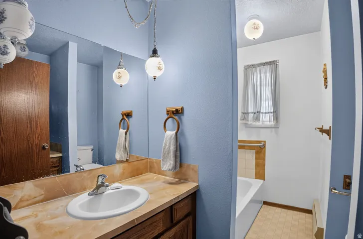Bathroom featuring a full vanity with an integrated sink, a large mirror, and a built-in bathtub with tiled surround