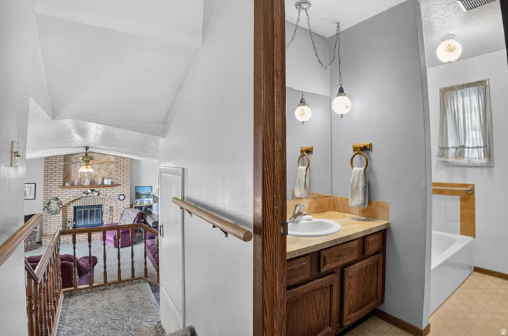 Bathroom vanity with wood-finish cabinetry, integrated sink, and pendant lighting