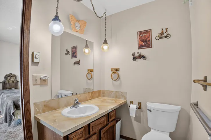 Vanity with integrated sink and countertop, wood-finish cabinetry, and wall-mounted mirror