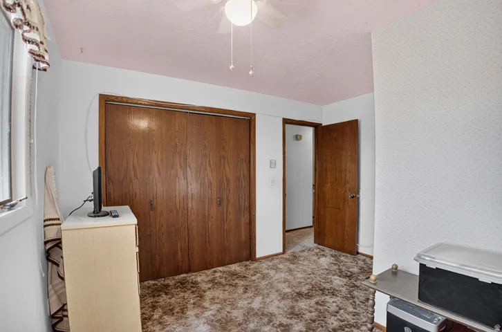 Carpeted flooring, wood-finish closet doors, wood-finish interior door, textured ceiling, window with trim