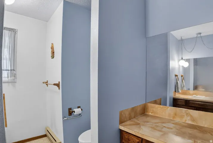Built-in vanity with a stone-finish countertop and mirrored wall