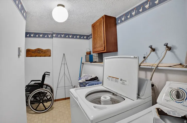 Laundry area with a mounted wall cabinet, light blue walls, and durable flooring