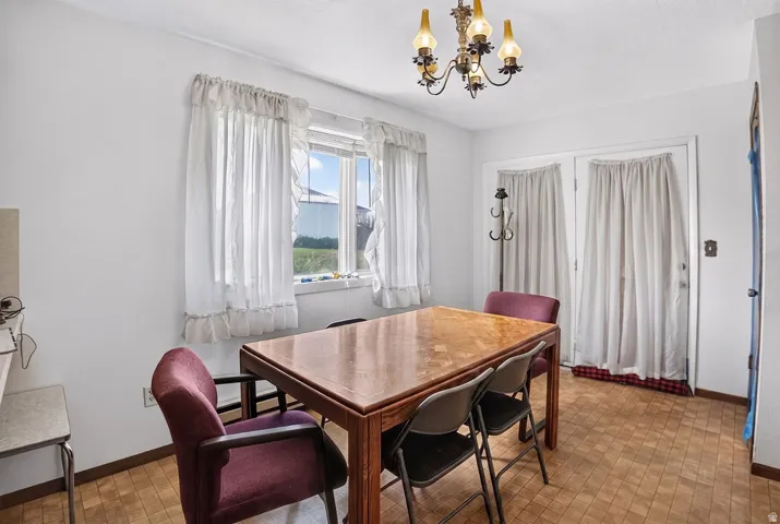 Recessed window with white trim, double French doors, wood-finish flooring, and a ceiling-mounted chandelier