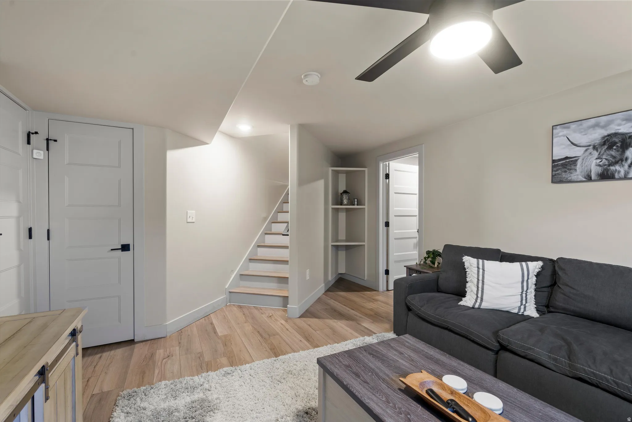 Wood-finish flooring throughout, recessed lighting, ceiling fan with integrated light, built-in shelving, and light gray interior doors with matte black hardware