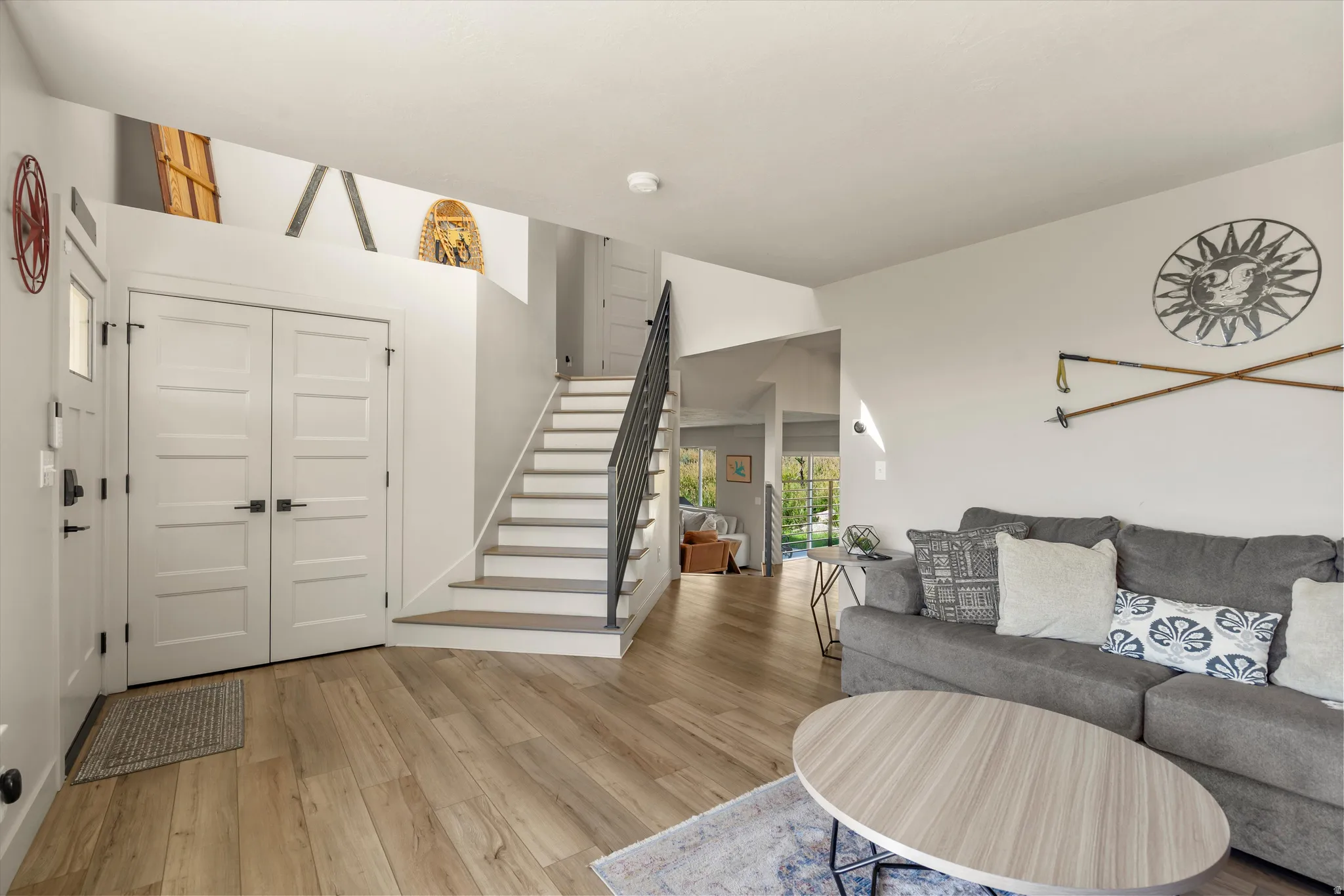 Light wood-finish flooring, white walls, and a staircase with a black metal railing