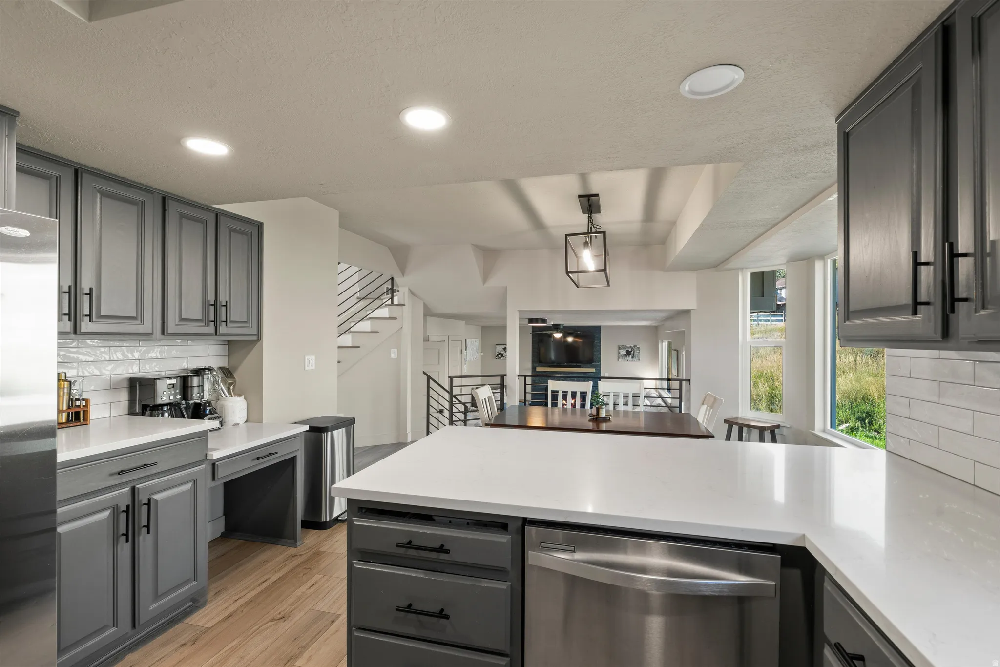 Kitchen featuring grey cabinetry, white countertops, a subway tile backsplash, and wood-finish flooring