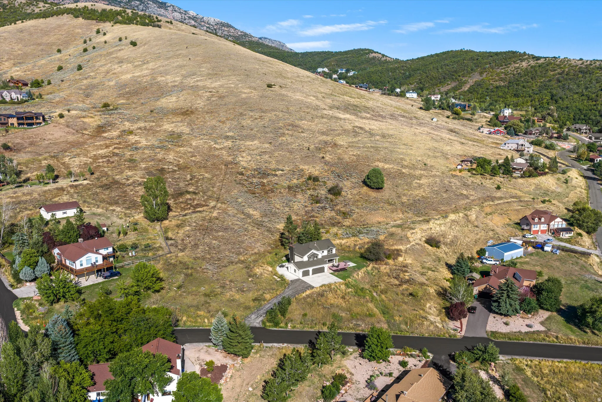 Sloping terrain featuring a two-story residence with an attached garage and paved driveway