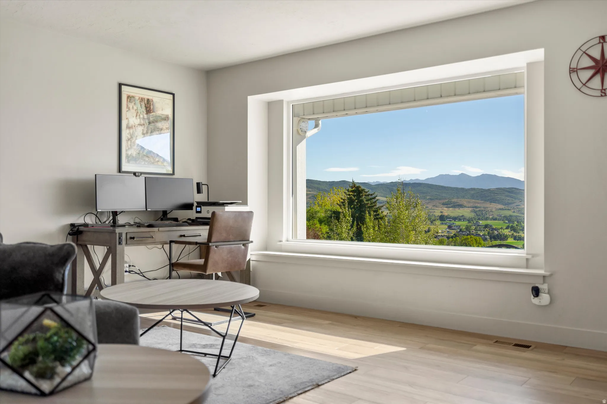Expansive window providing mountain and valley scenery, light wood-finish flooring, and neutral wall tones