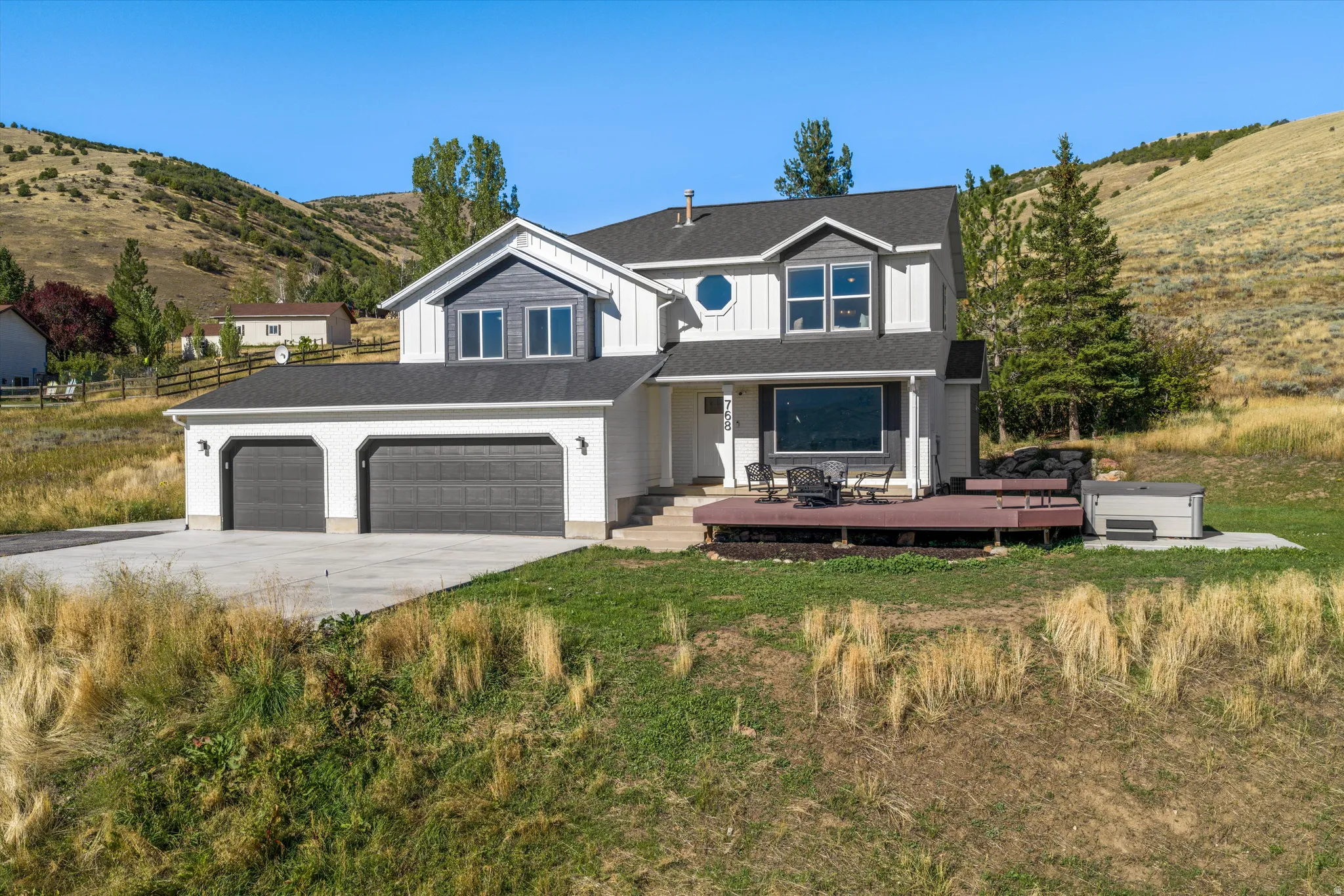 Two-story residence featuring a two-car garage, large deck, and distinct architectural elements including a prominent circular window