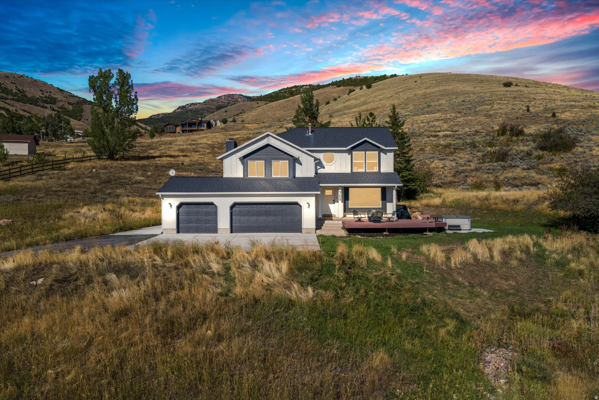 Two-story residence with a three-car garage, expansive wooden deck, and a distinctive circular window detail