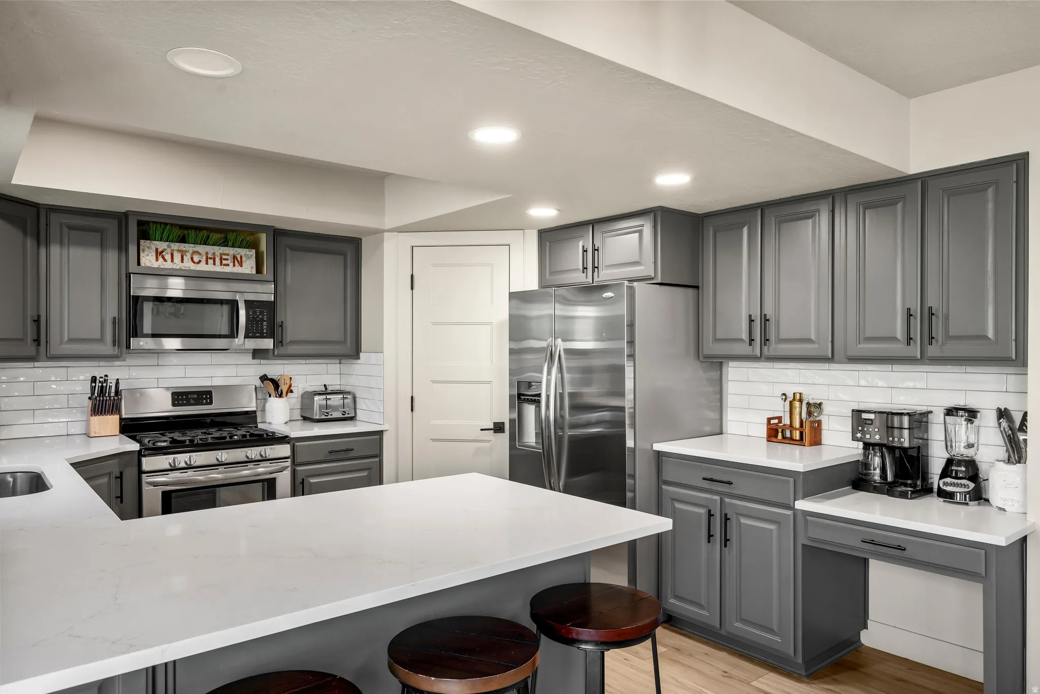 Kitchen featuring gray cabinetry, stainless steel appliances, white subway tile backsplash, white countertops, and recessed lighting