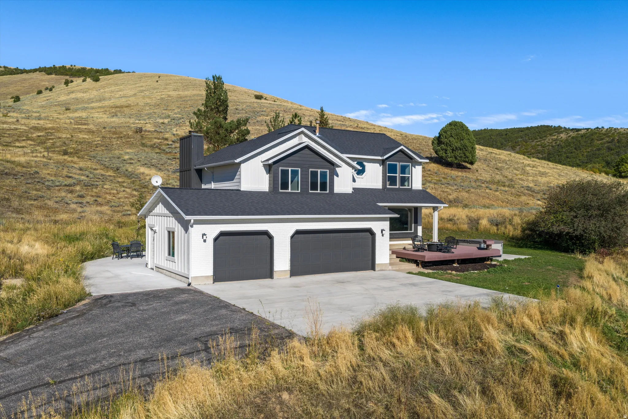 Two-story residence with a multi-gabled roofline, attached two-car garage, and an elevated wood-finish deck