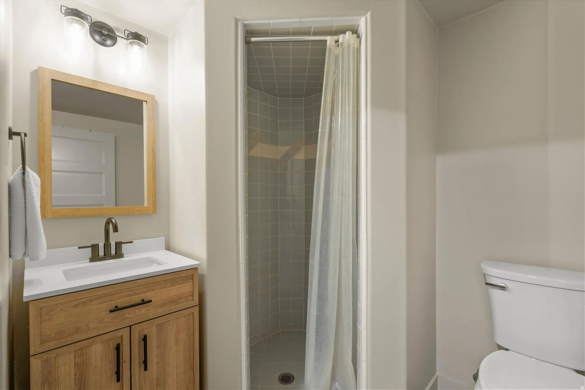 Wood-finish vanity with a white countertop and undermount sink