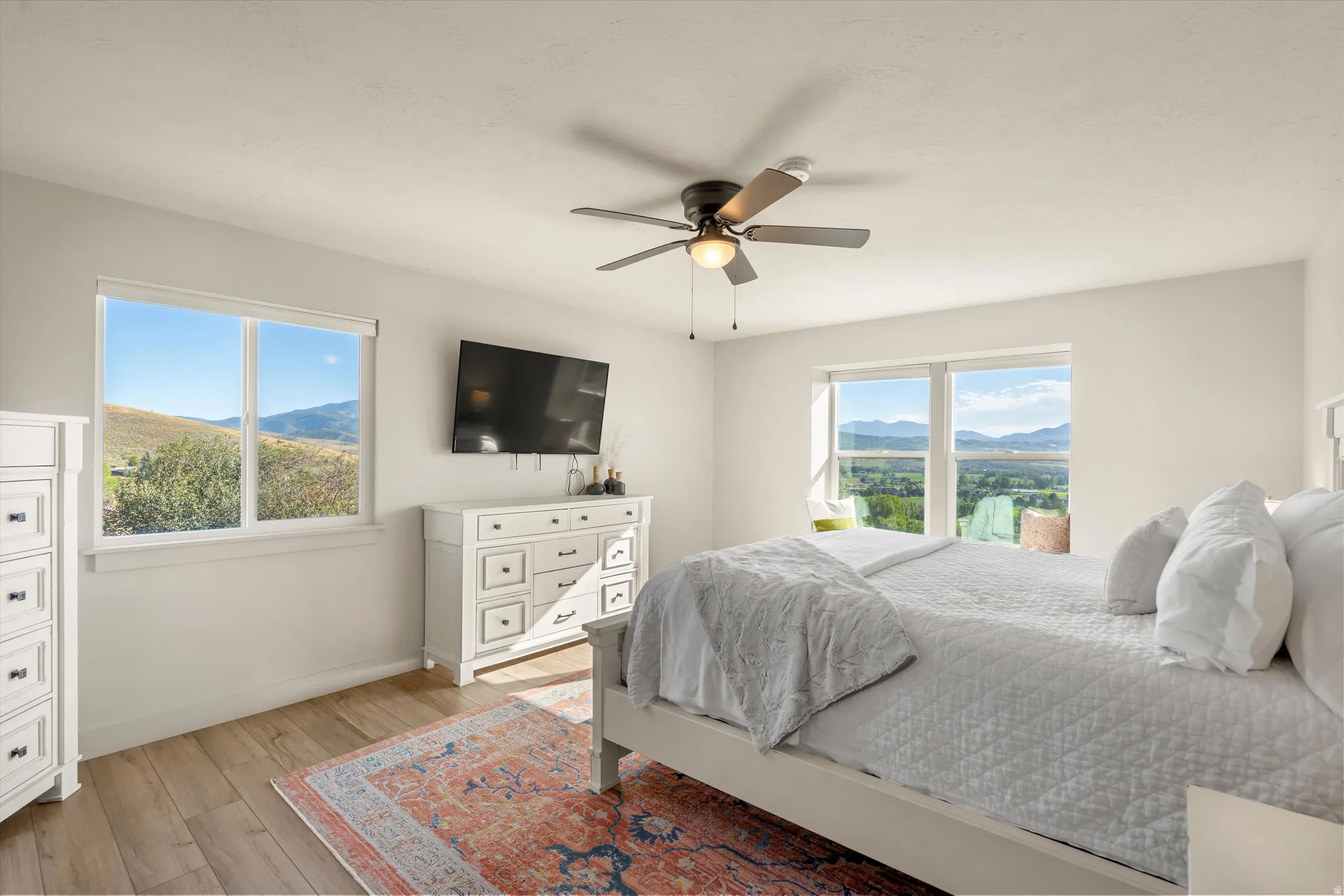 Wood-finish flooring, ceiling fan, and large windows offering expansive mountain and valley scenery