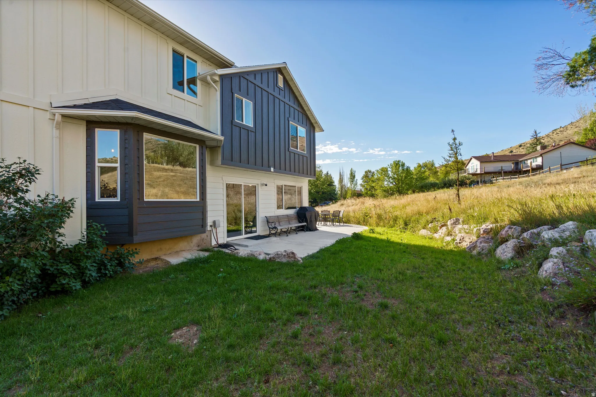 Two-tone exterior with a bay window, sliding glass doors, and a concrete patio
