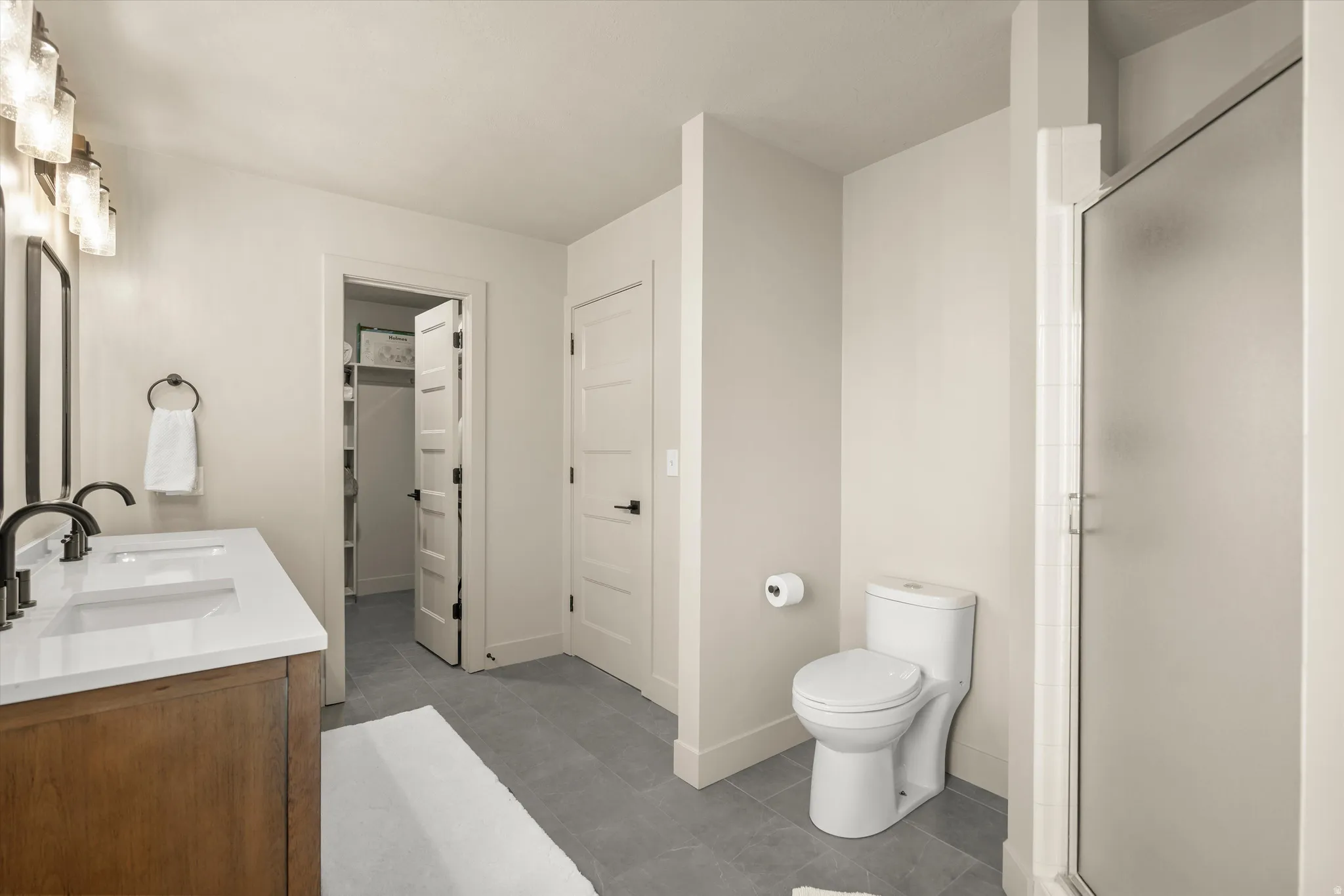 Dual vanity with wood-finish cabinetry, white countertops, and matte black fixtures