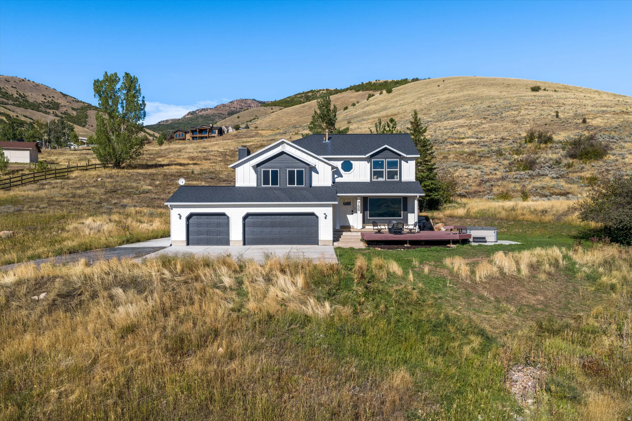 Modern two-story residence with a multi-pane window configuration, dual-bay garage, dark roof, and a built-in deck