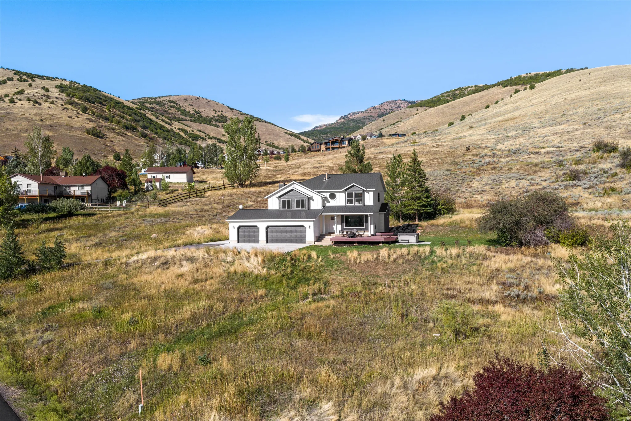 Two-story residence with a two-car garage, dark gray siding, and a wood-finish deck