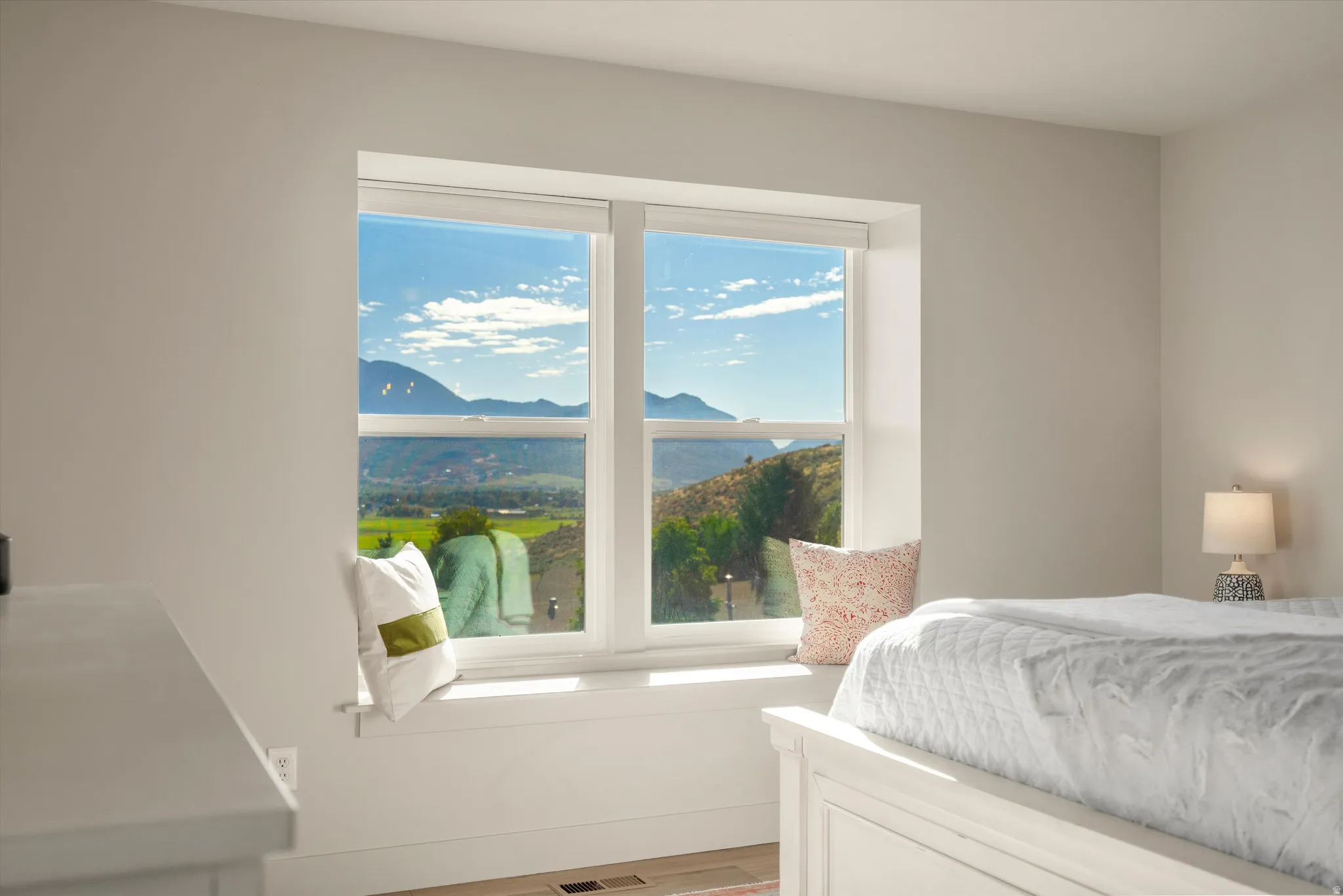 Large window with mountain and landscape scenery, offering a built-in window seat and roller shades