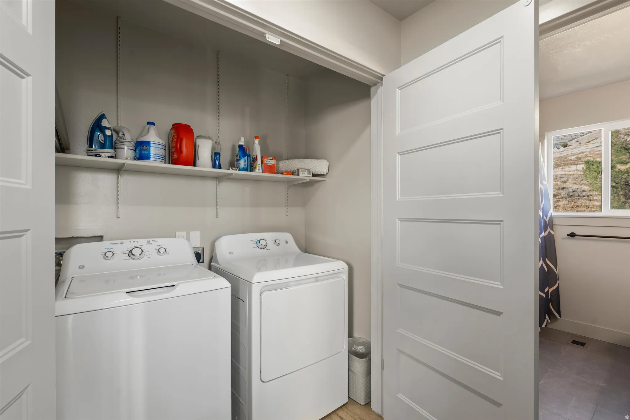 Dedicated laundry area with built-in shelving, top-load washer, and dryer