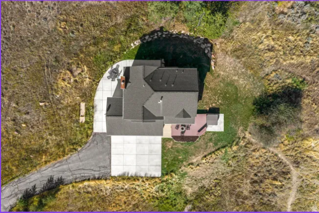 Pitched roof with dark shingles, concrete driveway, concrete patio, and a wooden deck