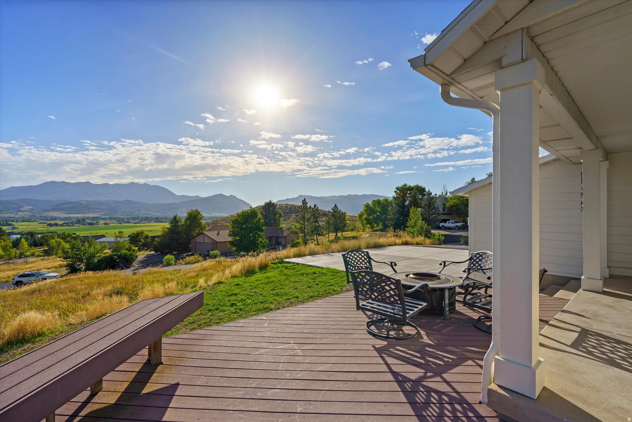 Expansive outdoor deck with mountain scenery, a gravel fire pit area, and a built-in bench
