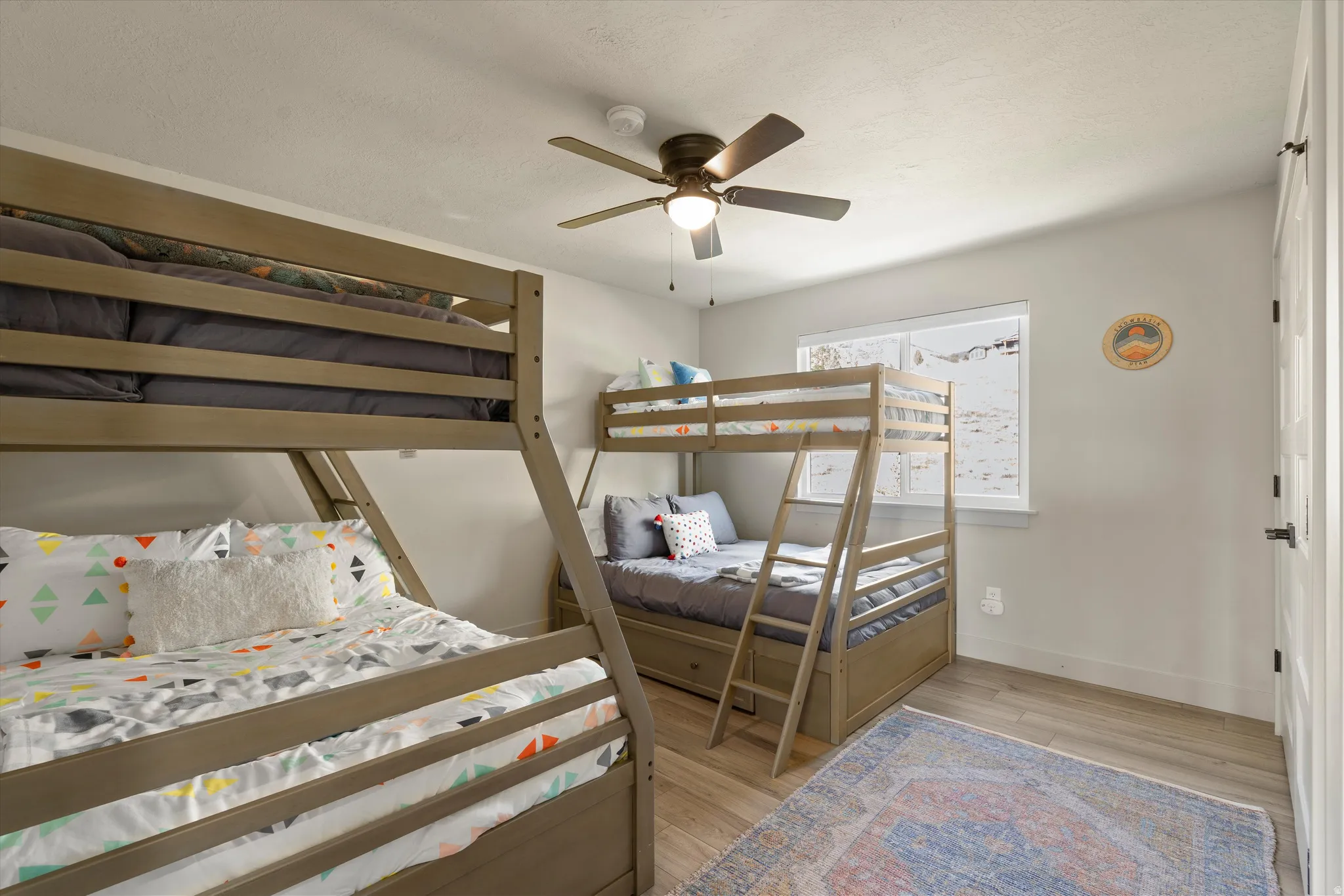Light-toned walls, wood-finish flooring, and a ceiling fan with integrated lighting