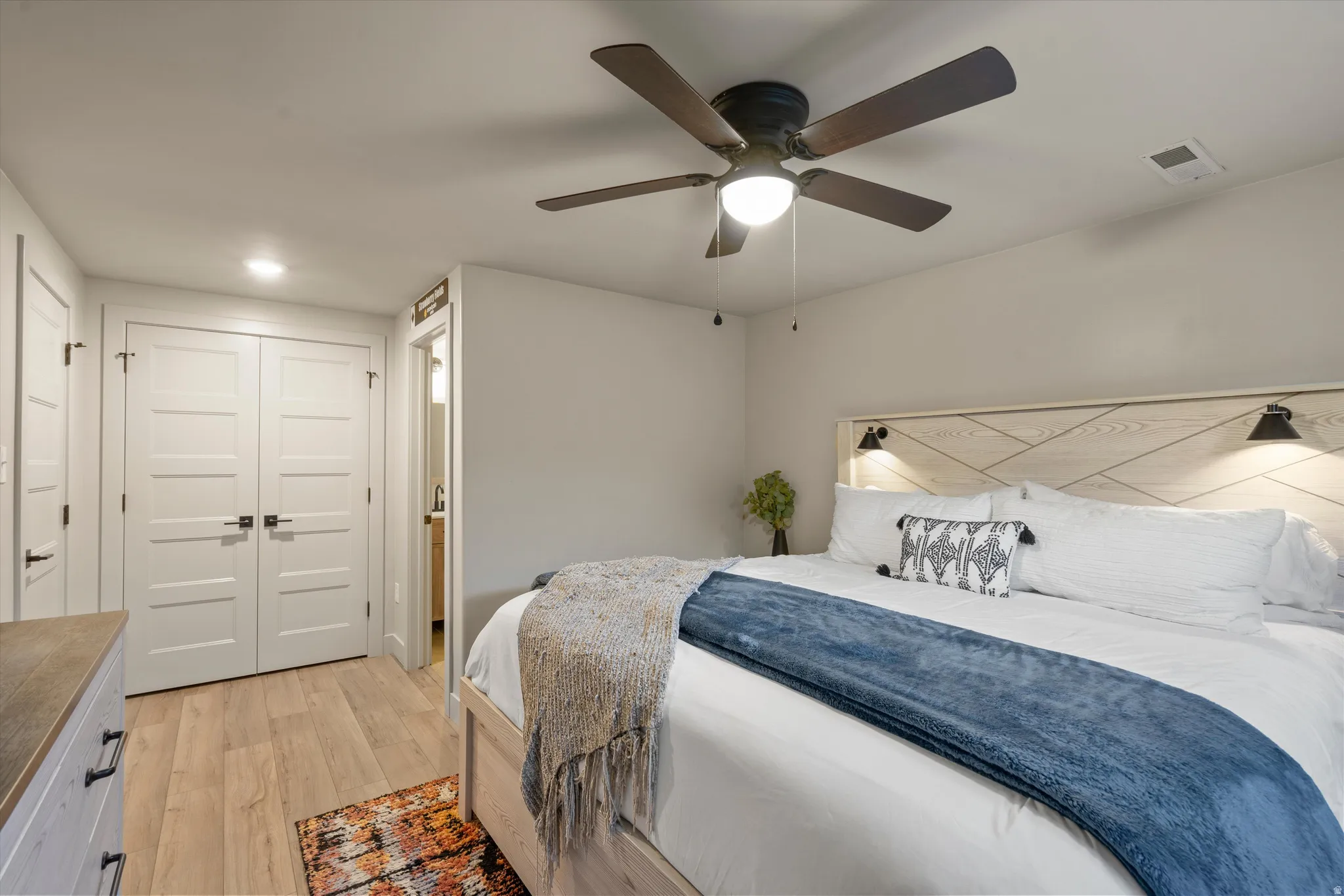 Wood-finish flooring, recessed lighting, ceiling fan with integrated light, and white paneled doors with black hardware