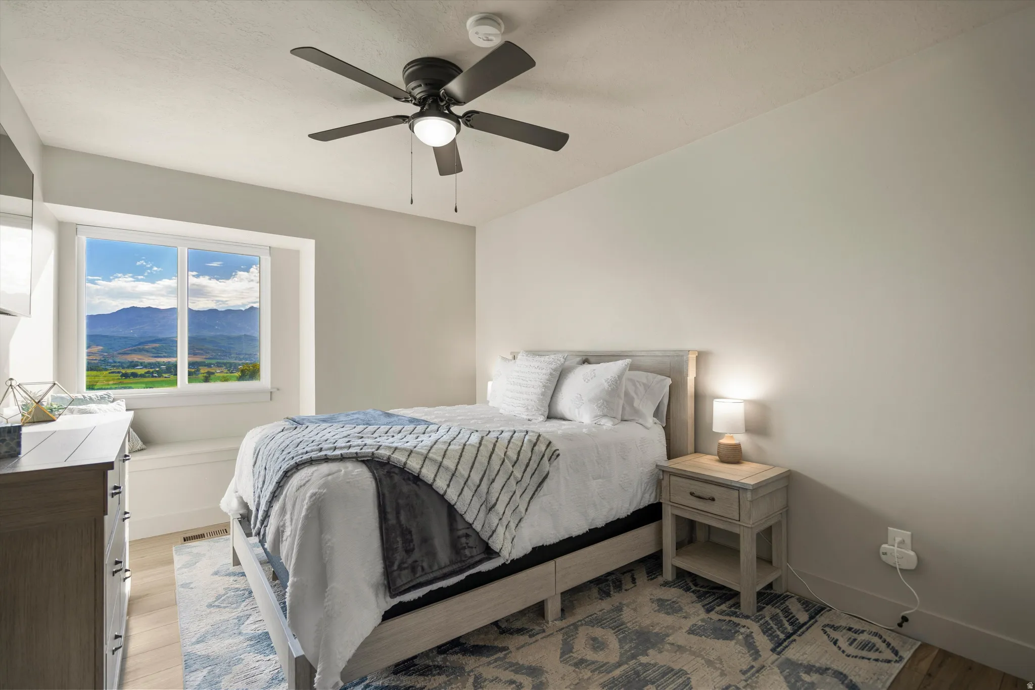 Recessed window with built-in seating, wood-finish flooring, and a ceiling fan with integrated lighting