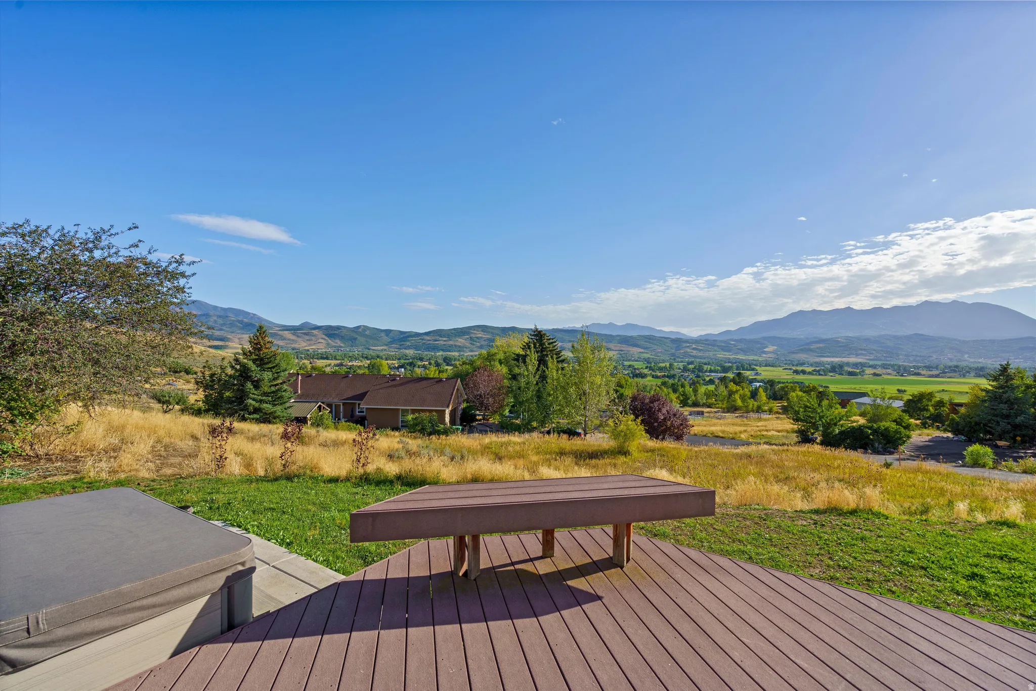 Expansive composite deck featuring built-in bench seating and a hot tub