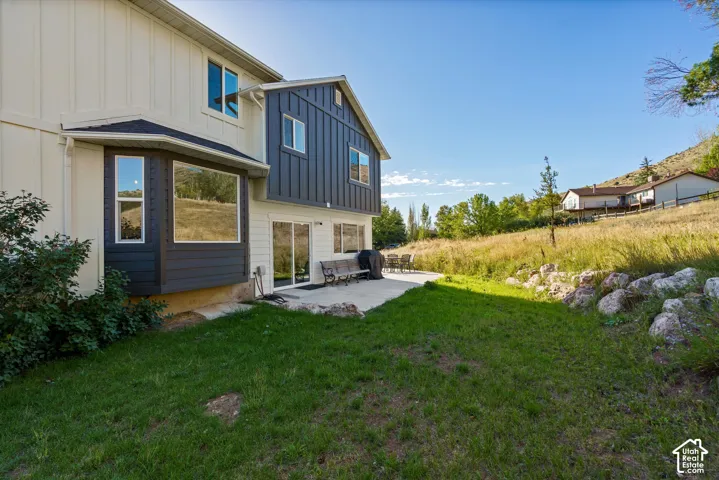 Two-tone exterior with a bay window, sliding glass doors, and a concrete patio