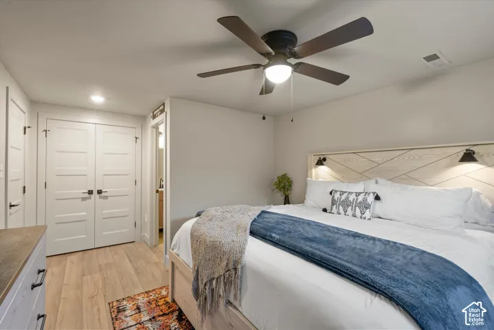 Wood-finish flooring, recessed lighting, ceiling fan with integrated light, and white paneled doors with black hardware