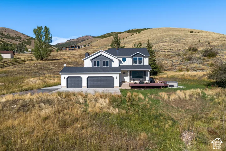 Modern two-story residence with a multi-pane window configuration, dual-bay garage, dark roof, and a built-in deck