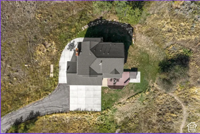 Pitched roof with dark shingles, concrete driveway, concrete patio, and a wooden deck