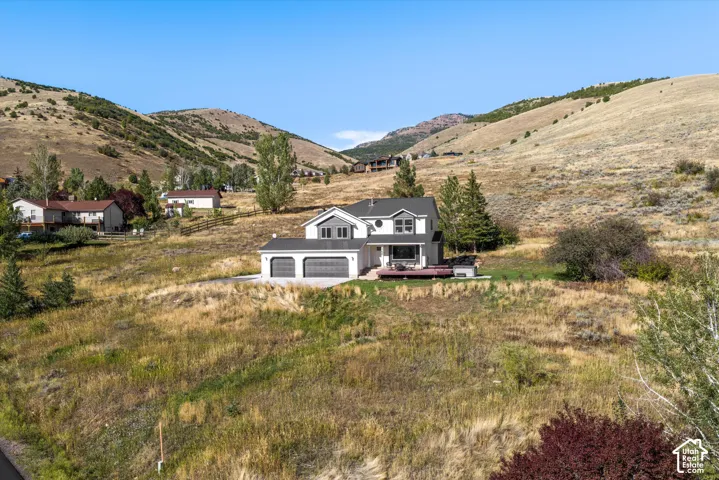 Two-story residence with a two-car garage, dark gray siding, and a wood-finish deck