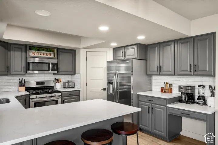 Kitchen featuring gray cabinetry, stainless steel appliances, white subway tile backsplash, white countertops, and recessed lighting