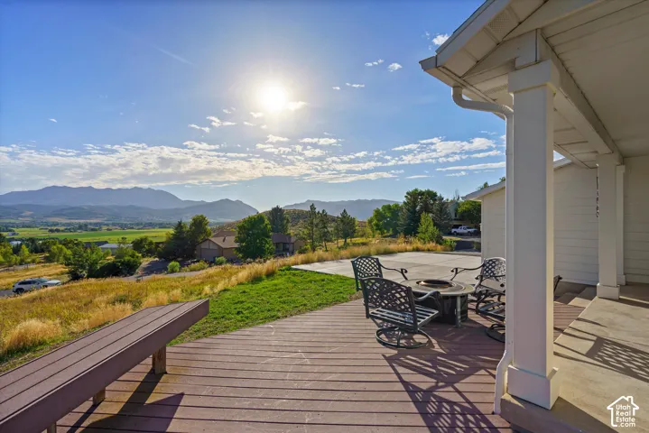 Expansive outdoor deck with mountain scenery, a gravel fire pit area, and a built-in bench